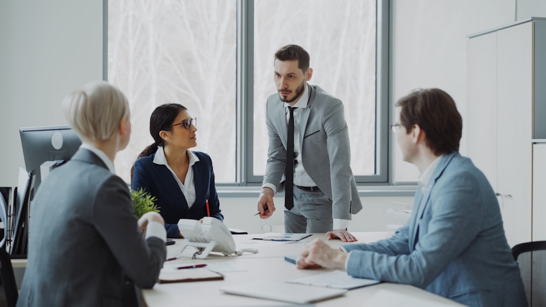 services-04 Businesswoman discussing reports with male and female colleagues sitting at the table in modern office indoors