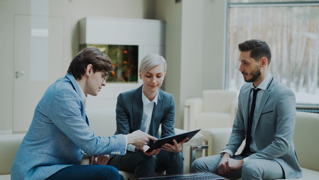 our-stories Panning shot of businessman discussing financial reports with female and male business partners sitting on sofa in modern office hall with indoors